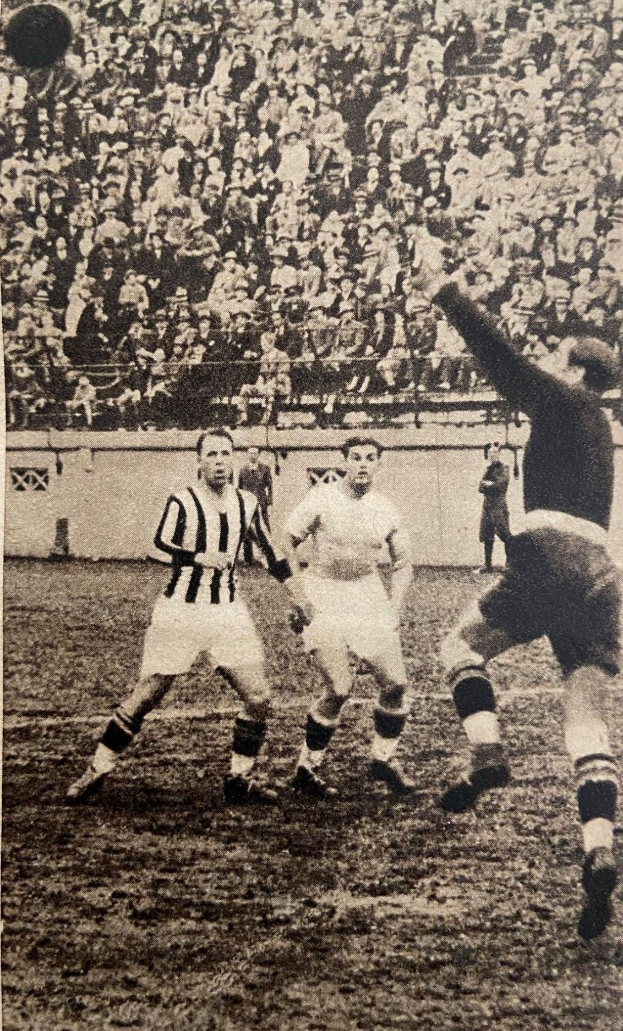 Schwarzes und weißes Foto von Männern, die Fußball spielen, mit Zuschauern auf den Tribünen und einer Wand dahinter, beschriftet mit "Newcastle United v West Bromwich Albion".