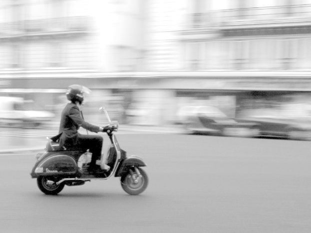 Eine Person, die ein Scooter auf der Stra√üe f√§hrt.
