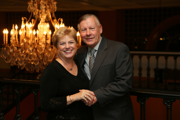 Ein Mann und eine Frau lächeln, mit einem Kronleuchterlicht dahinter.