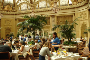 Eine Gruppe von Menschen, die an Tischen essen in einem Saal mit Pflanzen drumherum.