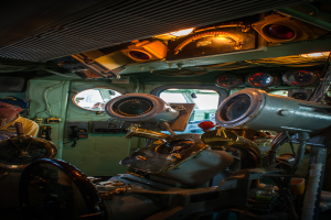 Das Innere eines Zuges mit Sitzen und verschiedenen Gegenständen zu sehen; eine Person in einem gelben T-Shirt steht auf der linken Seite des Bildes.