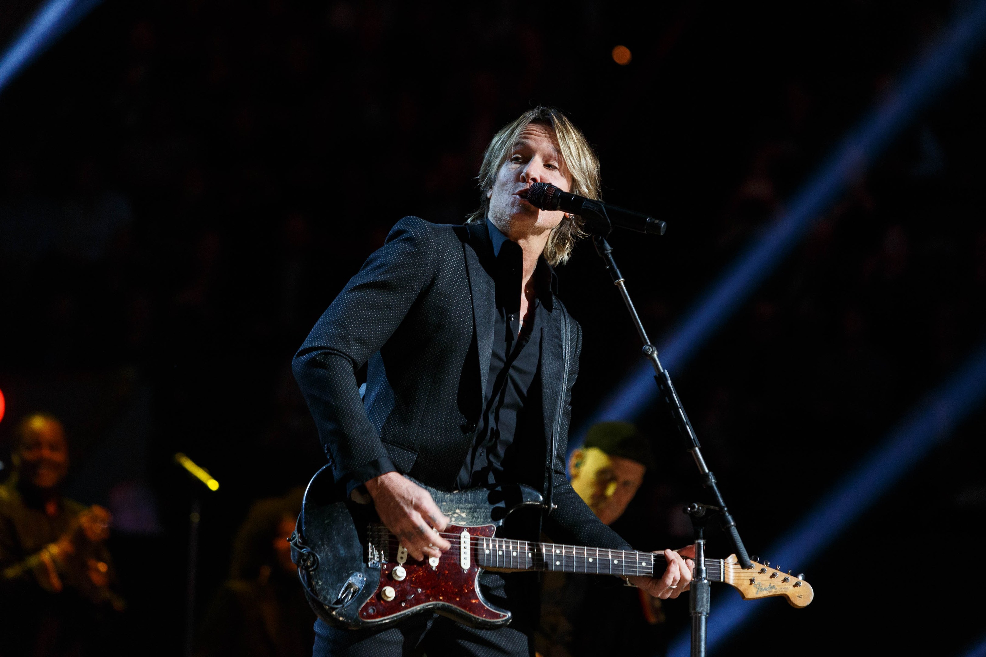 Keith Urban performs auf der Bühne im Joint im Hard Rock Hotel & Casino in Las Vegas, spielt Gitarre mit einem Mikrofon vor sich und Bandmitgliedern im Hintergrund bei gedämpfter Beleuchtung.
