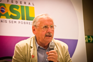 Eine Person, die in ein Mikrofon spricht und hinter sich ein Banner mit dem Wort 'Bundes' trägt.