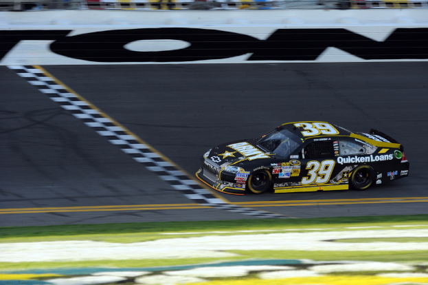 Ein Rennauto auf einer Straße mit Gras am Boden, mit Text auf dem Auto.