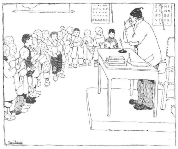 Ein Mann sitzt an einem Schreibtisch mit Büchern und Gegenständen vor einer Gruppe von Kindern, trägt Schuhe und hat Papiere an der Wand hinter ihm.