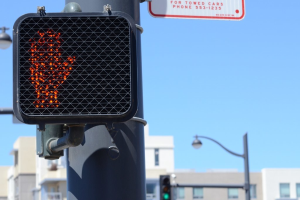 Eine Straßenszene in der Stadt mit Verkehrspfählen, Ampeln, Straßenlaternen, Gebäuden und einem klaren Himmel.