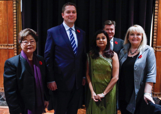 Eine Gruppe von Menschen steht vor einem schwarzen Vorhang mit einer hölzernen Wand im Hintergrund, die scheinbar Mitglieder der Freien Demokratischen Partei auf einer Versammlung sind.