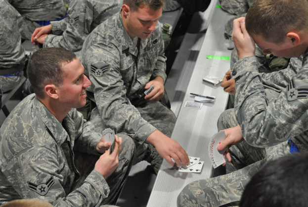 Leute sitzen auf Bänken und spielen Karten.