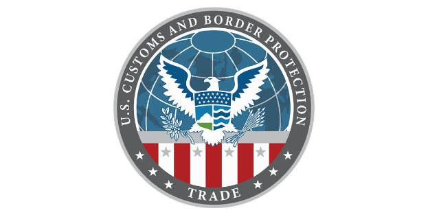Logo der U.S. Zoll- und Grenzschutzbehörde Handel - Ein blauer Kreis mit einem weißen Stern, einer weißen Taube mit ausgebreiteten Flügeln und dem Text "U.S." darüber, alles auf einem weißen Rand.