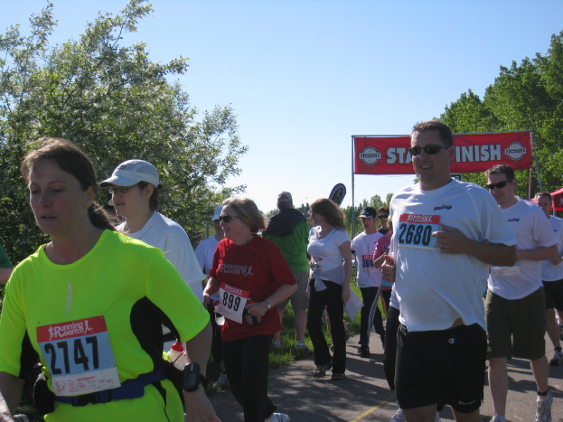 Eine Gruppe von Kindern, die bei einem Marathonlauf rennen, mit einem roten Banner und Bäumen im Hintergrund.