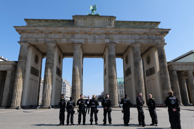 Gruppe von Polizisten vor dem Brandenburger Tor in Berlin, Deutschland, mit dem Torbogen, Säulen und Statue.