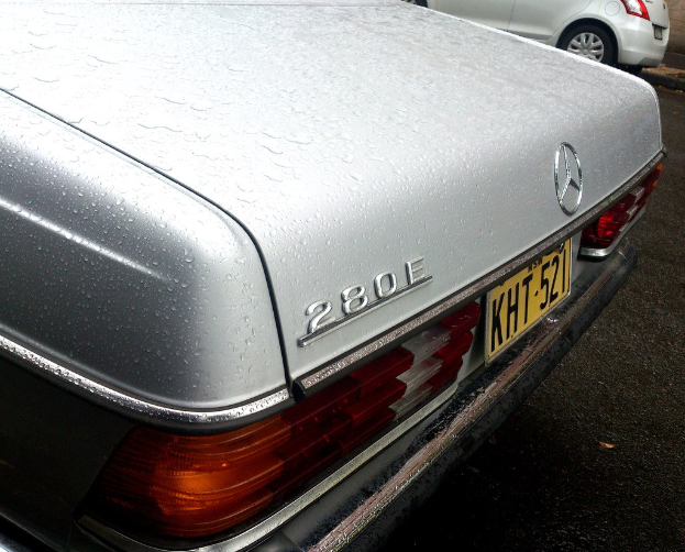 Mercedes-Benz-Logo auf einem Fahrzeug, das auf einer Straße neben einem anderen Fahrzeug fährt.