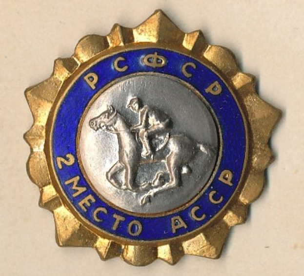 Gold- und blaues Abzeichen mit einem Pferd und Reiter in der Mitte, umgeben von Text.