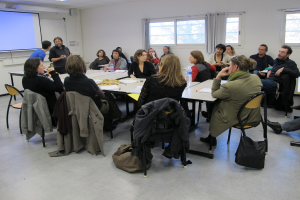 Eine Gruppe von Menschen, die sich unterhält, mit zwei Individuen im Hintergrund, die miteinander sprechen.