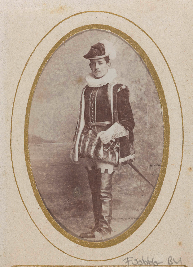 Ein altes Foto eines Mannes in traditioneller schottischer Kleidung, einschließlich Kilt, weißem Hemd, schwarzem Weste und schwarzem Hut, der entschlossen eine Waffe hält.