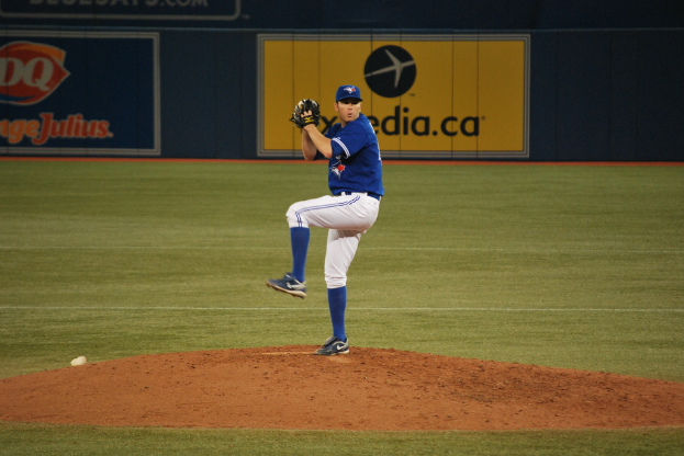 Ein Spieler steht auf dem Feld und hält einen Ball, im Hintergrund eine große Fahne mit Text und Bildern.