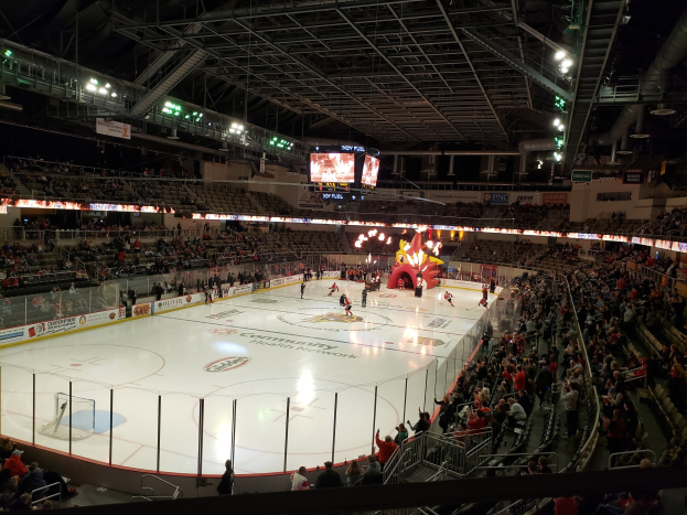 Eishockeyspiel in einer großen Arena mit Zuschauern, die Eisfläche von einem Zaun umgeben, Banner, Deckenbeleuchtung und zwei Bildschirme; die Location ist die Nationwide Arena.