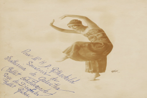 Ein altes Foto einer Frau in einem Kleid, die anmutig tanzt, mit ausgestreckten Armen und Beinen, einem Dutt und einem friedlichen Gesichtsausdruck, mit Text auf dem Papier.