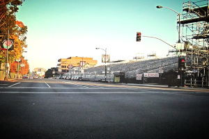 Eine Straße mit einer Verkehrsampel und Gerät auf der rechten Seite, Warnschilder und mehrere Fahrzeuge auf der linken Seite und Bäume im Hintergrund.