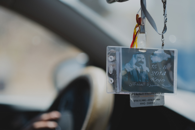 Eine Person fährt ein Auto mit einem ID-Kartenanhänger am Lenkrad, ihre Hand ist auf der linken Seite zu sehen, mit einem unscharfen Hintergrund.