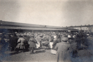 Eine große Menschenmenge, die wie Flüchtlinge aussieht, steht vor einem Gebäude unter einem klaren Himmel, dargestellt in Schwarz-Weiß.