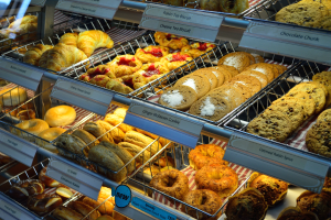 Eine Vitrine voller verschiedener Gebäcke, darunter Kuchen und Cookies, mit Schildern, die die Art der Backwaren angeben.