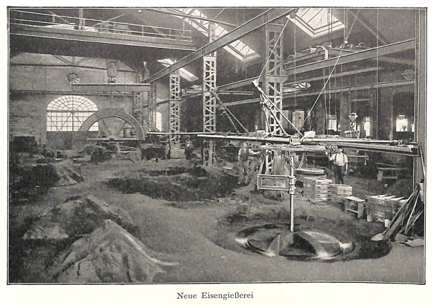 Schwarzes und weißes Foto eines Fabrikinneren mit Arbeitern, die Maschinen bedienen, Metallstangen und -rohre, beschriftet mit "Neue Eisenglebeerei, die erste Fabrik in Deutschland" unten.