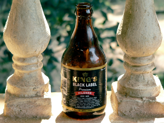 Eine schwarze Flasche mit der Aufschrift "Kings" ist zwischen zwei unbestimmten Gegenständen platziert.