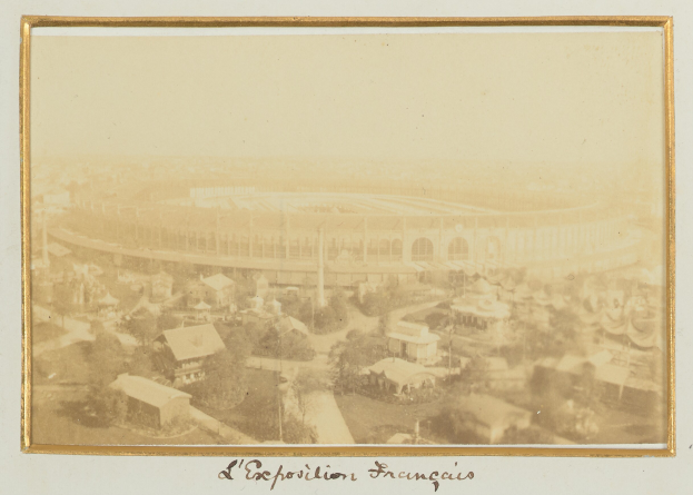 Altes Schwarz-Weiß-Foto eines Stadions in städtischer Umgebung mit umliegenden Gebäuden, Bäumen und Strommasten; Text erscheint unten.