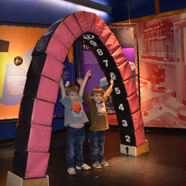 Kinder spielen auf einer lustigen Attraktion mit Brettern, die auf einem Boden stehen.
