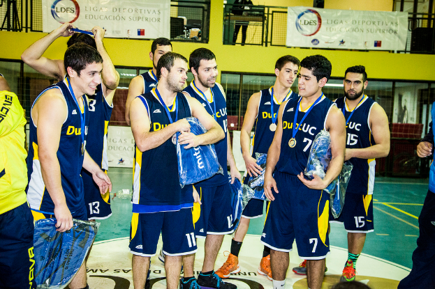 Eine Gruppe von Menschen, einige mit Medaillen und Gegenst├Ąnden in der Hand, steht vor Bannern und Gel├Ąndern.