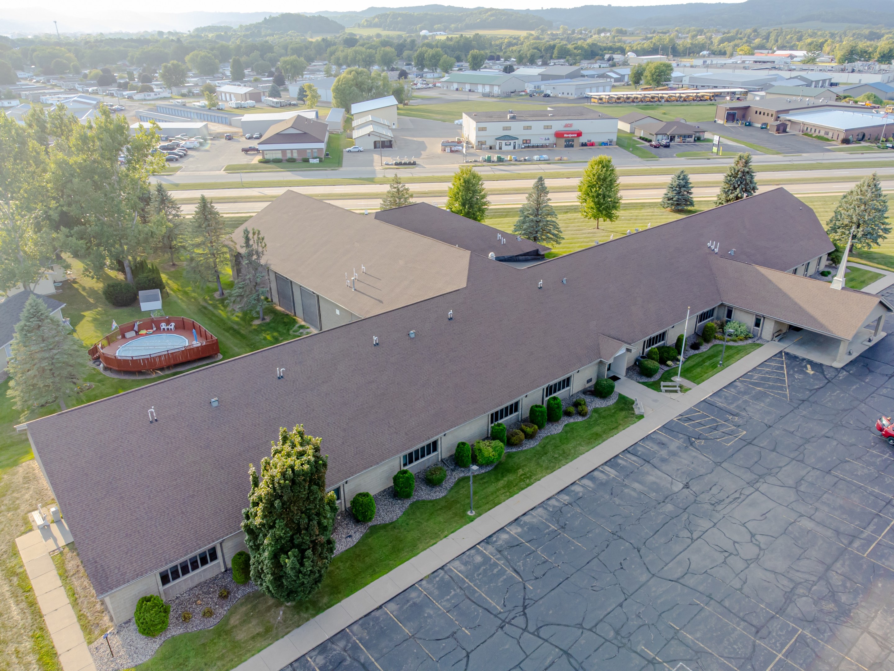 Luftaufnahme eines großen Seniorenwohnheims an der University of Kentucky, das einen Parkplatz, umliegende Vegetation, Fahrzeuge auf der Straße, entfernte Hügel und einen klaren blauen Himmel zeigt.