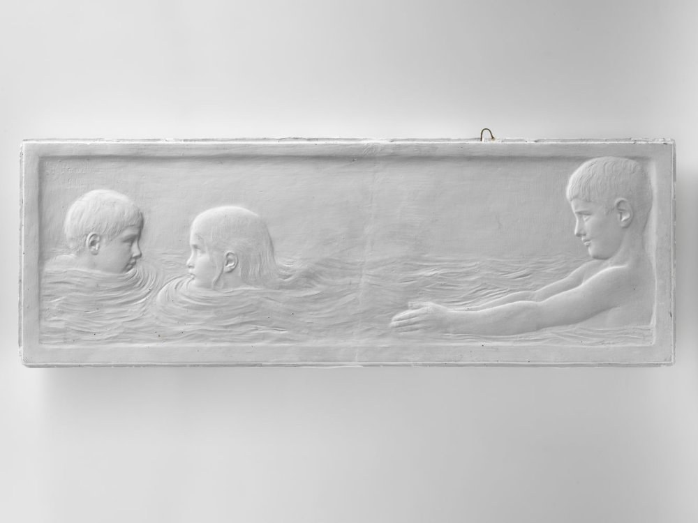 Drei Kinder schwimmen in einem Gewässer mit einer Wand im Hintergrund.