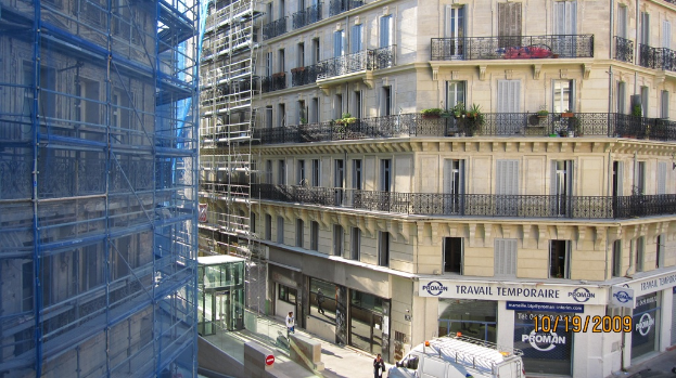 Ein großes Gebäude in Bau auf der linken Seite, mit einem Geschäft auf der rechten Seite im Erdgeschoss