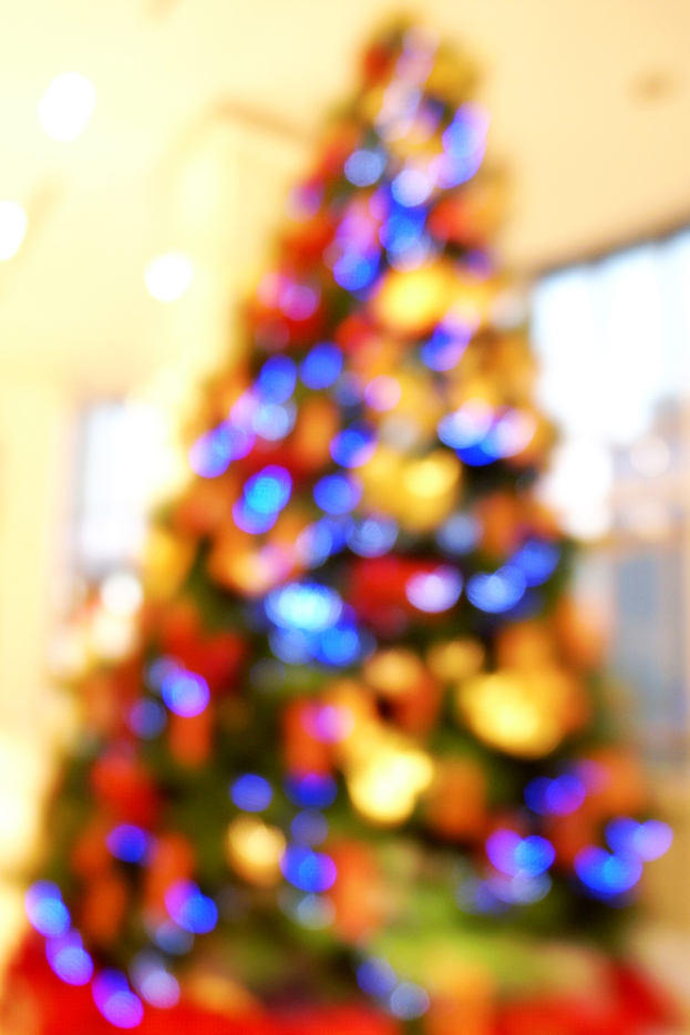 Ein unscharfer Schnappschuss eines Indoor-Weihnachtsbaums, der mit Lichtern und Schmuck geschmückt ist.