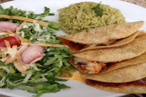 Ein weißer Teller mit Reis, Gemüse und Snacks.