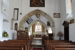 Ein Kircheninneres mit Blumenvasen, Bänken, Fotorahmen und Lichtern.