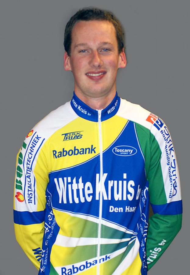 Ein männlicher Athlet, der für ein Foto posiert, mit sichtbaren Sponsorenlogos auf seinem Hemd.
