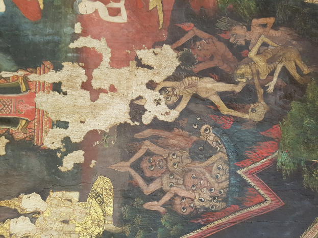 Ein farbenfrohes Wandgemälde in einem thailändischen buddhistischen Tempel, das Menschen und Tiere einschließlich eines Löwen, einer Giraffe, eines Affen und eines Zebras in einer üppigen grünen Landschaft mit Bäumen und fernen Bergen zeigt.