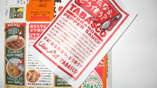 Ein Prospekt, der Pfeffersoße bewirbt, mit einem darunter liegenden Blatt, auf dem Curry-Anzeigen zu sehen sind.