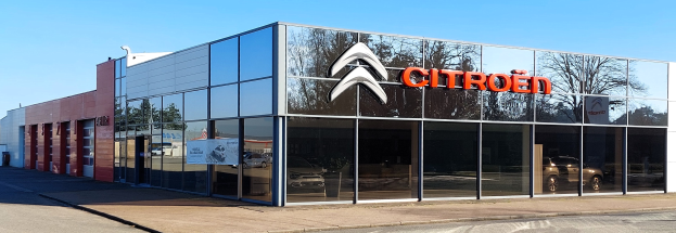 Außenansicht eines Citroën-Händlergebäudes mit Glaswänden und -türen, einer Straße davor und einem klaren blauen Himmel.