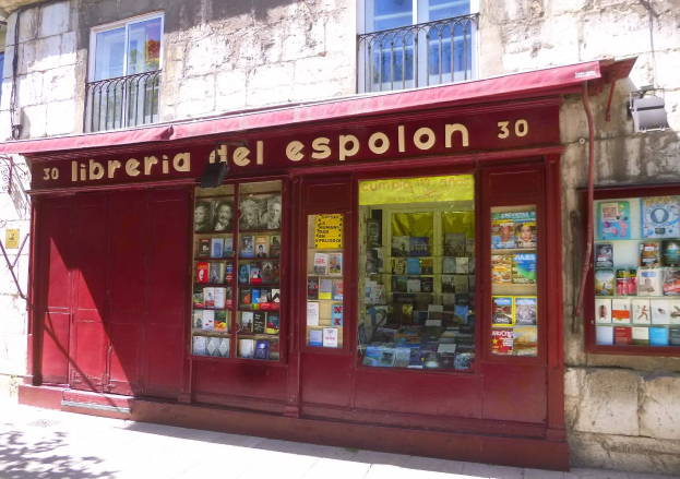Ein zweistöckiges Gebäude mit einem roten Markisenladen, der mit "Libreria del Espolon" beschriftet ist und ordentlich sortierte Bücher im Inneren zeigt.