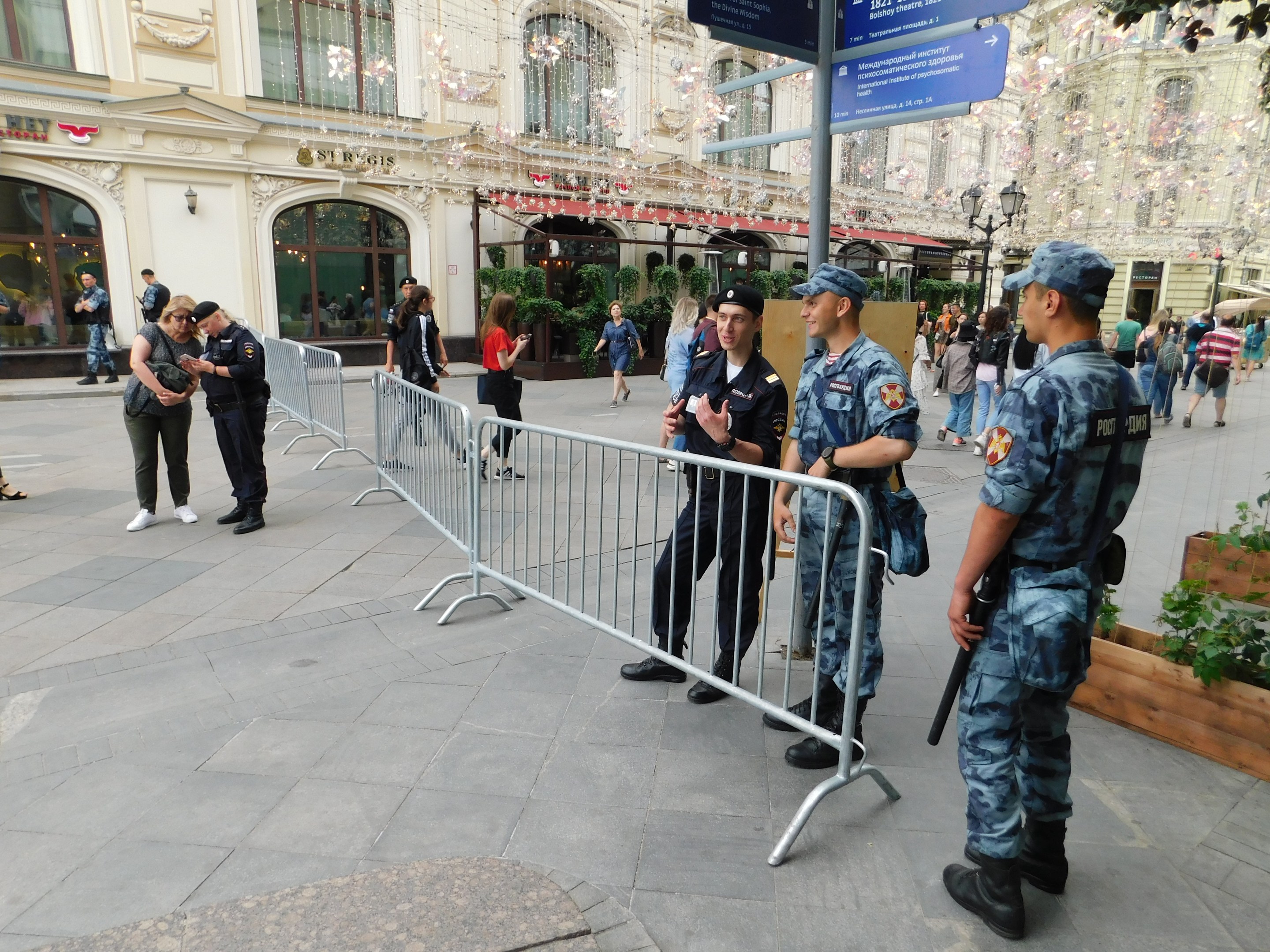 Polizeibeamte in Uniform stehen vor einer Menge, einige halten Waffen, mit Absperrungen und Schildern im Vordergrund und Gebäuden, Laternenmasten und Bäumen im Hintergrund während eines Anti-Terror-Einsatzes in Wien, Österreich.
