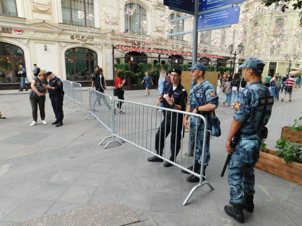 Polizeibeamte in Uniform stehen vor einer Menge, einige halten Waffen, mit Absperrungen und Schildern im Vordergrund und Gebäuden, Laternenmasten und Bäumen im Hintergrund während eines Anti-Terror-Einsatzes in Wien, Österreich.