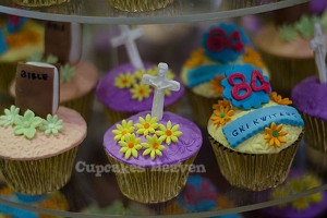Ein Buch und ein Kreuzsymbol werden auf einem Cupcake platziert, mit anderen Cupcakes im Hintergrund.