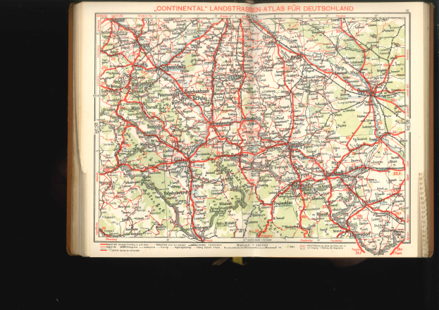 Ein aufgeschlagenes Buch mit einer detaillierten Deutschlandkarte mit Straßen und Autobahnen auf schwarzem Hintergrund.