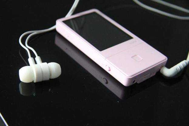 Ein pinker iPod mit weißen Ohrhörern auf einer schwarzen Oberfläche.