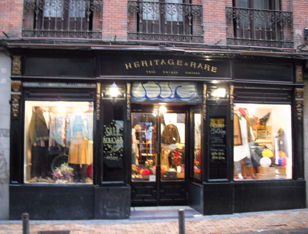 Heritage Boutique in Madrid mit Schaufensterpuppen, Außenbeschriftung und einer Straße unten.