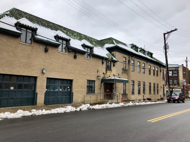 Großes Backsteingebäude mit einem grünen Dach an einer Straßenecke, umgeben von Fahrzeugen, Schnee, Strommasten, Bäumen und einem bewölkten Himmel, identifiziert als das ehemalige St. Louis Fire Station.