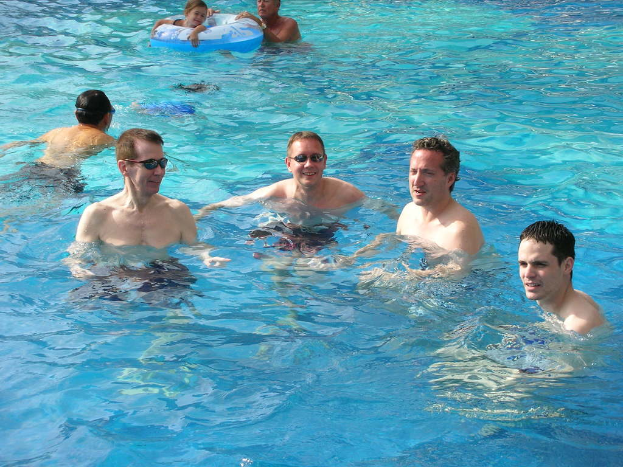 Mehrere Männer schwimmen im Wasser, während ein Mädchen mit einem Ballon schwimmt, den eine andere Person hält.